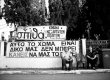 Two-old-people-stand-in-front-of-an-antigold-banner-in-Ierissos